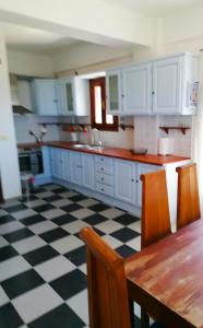 eine Küche mit weißen Schränken und einem schwarz-weiß karierten Boden in der Unterkunft Litani Villa in Raches