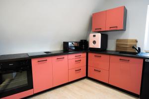 una cucina con armadi rossi e ripiani neri di Appartement de la marquise - Designed by C.M a Sélestat
