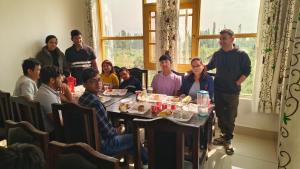 a group of people are sitting around a table at Hotel Gulsitara-Kunzer Gulmarg in Gulmarg