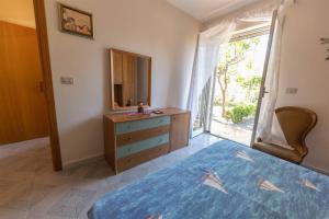 1 dormitorio con cama, tocador y espejo en Appartanvilla con giardino terrazzo e parcheggio privato, en Mascali