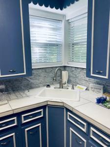 a kitchen with blue cabinets and a sink and a window at Xscapecation Oasis in Tulsa