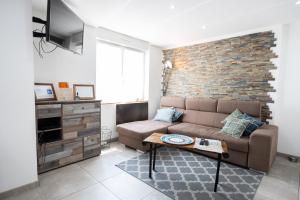 a living room with a couch and a brick wall at Appartement des Sorcieres - Witches Apartment in Sélestat