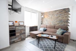 un soggiorno con divano e muro di mattoni di Appartement des Sorcieres - Witches Apartment a Sélestat