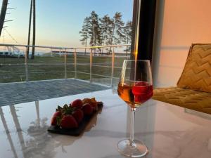 a glass of wine and a plate of strawberries on a table at Valkla Puhkekeskus - Merevaatega SVIIT in Salmistu