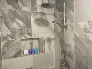 a shower in a bathroom with a marble wall at Valkla Puhkekeskus - Merevaatega SVIIT in Salmistu