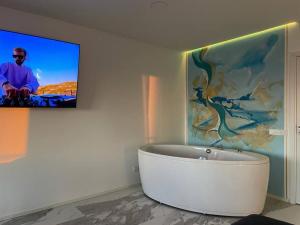 a bathroom with a bath tub and a tv on the wall at Valkla Puhkekeskus - Merevaatega SVIIT in Salmistu