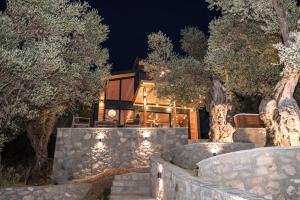 a house with a stone wall and trees at night at Villa Tramonto D'Oro in Ulcinj