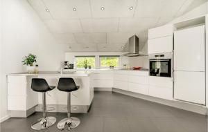 una cocina con armarios blancos y taburetes negros en Lovely Home In Hjrring With Kitchen, en Vester Vidstrup