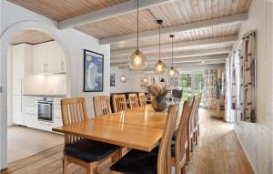 Cozy Home In Rm With Indoor Swimming Pool في رومو كيركيبي: غرفة طعام ومطبخ مع طاولة وكراسي خشبية