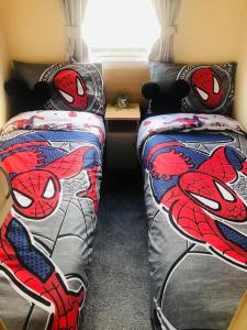 1 dormitorio con 2 camas con almohadas de superman en 8 person static caravan en Heysham