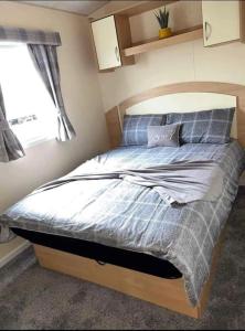 1 dormitorio con 1 cama con edredón azul y ventana en 8 person static caravan en Heysham