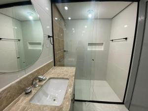 a bathroom with a sink and a shower with a mirror at Flat no coração de brasília in Brasilia