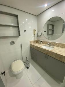 a bathroom with a toilet and a sink and a mirror at Flat no coração de brasília in Brasilia