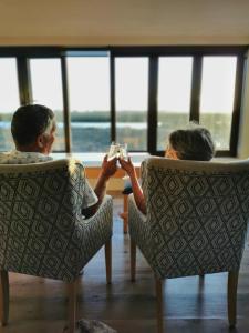 um homem e uma mulher sentados em cadeiras a beber vinho em Lermitage Game Lodge - Solar Power em Velddrif