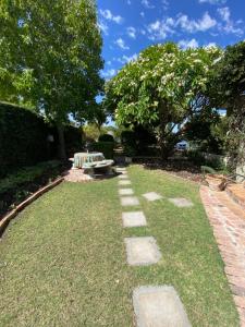 a garden with a bench and grass and trees at Vredelust Cottage in Bellville