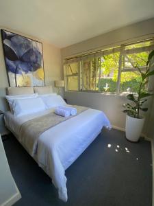 a bedroom with a large white bed and a window at Vredelust Cottage in Bellville