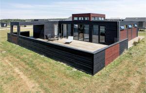 a black house with a deck on a field at Three-Bedroom Holiday Home In Lokken in Løkken