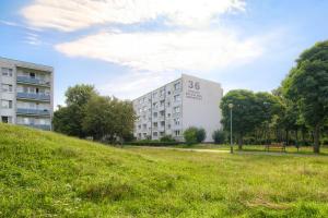 a building on a grassy hill next to a building at Blue Morpho Piątkowo Apartment in Poznań