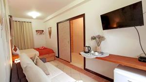 sala de estar con sofá y TV en la pared en Solar das Pétalas Guest House, en Florianópolis
