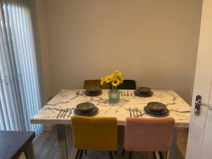 a dining room table with a vase of flowers on it at Luxury Rooms in a 3-Bedroom House, Living Room, Kitchen, Big garden only 8mins away from Coventry City Centre in Coventry