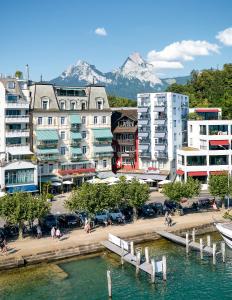 una ciudad con puerto deportivo y edificios con montañas en Hotel Schmid & Alfa, en Brunnen