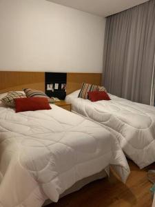 圣保罗Flat confortável próx Ibirapuera e Jardins com garagem的卧室内的两张床,配有白色床单和红色枕头