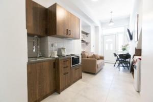a kitchen with wooden cabinets and a living room at Aigli Guest House in Gythio