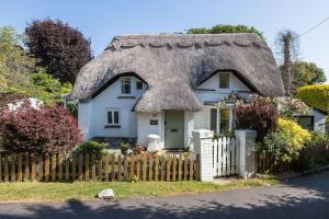 una casa con techo de paja y valla en Smugglers Cottage, en Barton-on-Sea