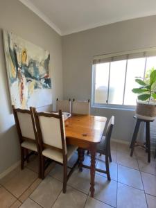 uma sala de jantar com uma mesa de madeira e cadeiras em Vredelust Cottage em Bellville