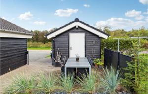 a small black shed with a table in a garden at Cozy Home In Hemmet With Sauna in Hemmet
