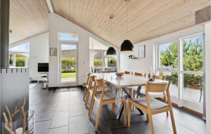 a dining room with a table and chairs and windows at Cozy Home In Hemmet With Sauna in Hemmet