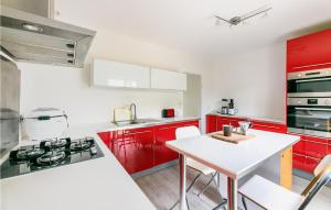 eine Küche mit roten Schränken und einem weißen Tisch in der Unterkunft Amazing Home In Jou Les Tours With Kitchen in Joue-les-Tours