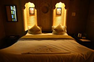 1 dormitorio con 1 cama grande con sábanas y almohadas blancas en Hotel Navodaya Jaisalmer, en Jaisalmer