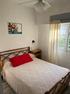 a bedroom with a bed with a red pillow on it at Junto Al Mar Y Centro De Santa Clara, Dos Casas in Santa Clara del Mar