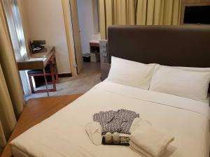 a bedroom with a white bed and a desk at Amrise Hotel Kitchener in Singapore