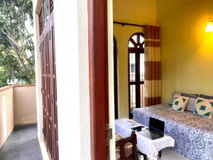 Jayalath Homestay and Apartments في غالي: غرفة مع شرفة مع طاولة وجهاز كمبيوتر محمول