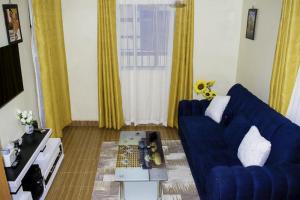 Beleen Homes II في نيروبي: غرفة معيشة مع أريكة زرقاء وطاولة