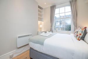 Un dormitorio con una gran cama blanca y una ventana en Stylish first floor 1BR flat in Notting Hill, en Londres
