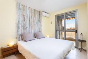 a bedroom with a large white bed and a window at El Medano in El Médano
