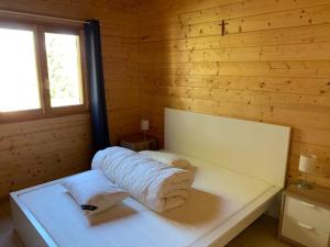 ein weißes Bett in einem Holzzimmer mit Handtüchern in der Unterkunft Chalet de la Rua, Risoul Village in Risoul
