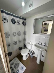 a bathroom with a toilet and a sink and a mirror at Departamento centro Quillota con estacionamiento in Quillota