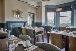 a dining room with tables and chairs and windows at The Lansdowne, Eastbourne in Eastbourne