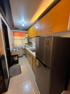 La cuisine est équipée d'un réfrigérateur en acier inoxydable et de placards en bois. dans l'établissement One Oasis Condominium 2 Bedroom, à Davao