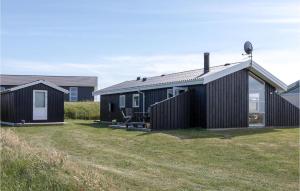 een zwart huis op een grasveld naast een gebouw bij Amazing Home In Lkken With Kitchen in Løkken