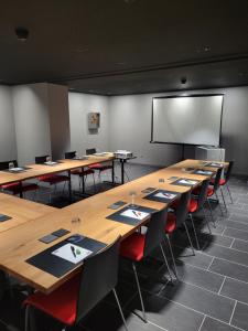 a classroom with long tables and chairs and a projection screen at Hotel Artist in Biel