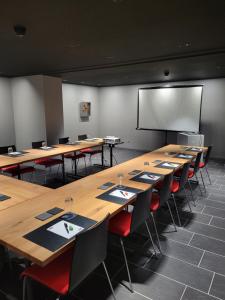 une salle de classe avec de longues tables et chaises et un écran de projection dans l'établissement Hotel Artist, à Biel