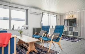 Stunning Home In Pandrup With Kitchen في Rødhus: غرفة معيشة مع كراسي زرقاء وطاولة وتلفزيون