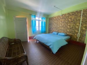 um quarto com uma cama azul e uma parede de tijolos em DPM HOMESTAY em Bomdila