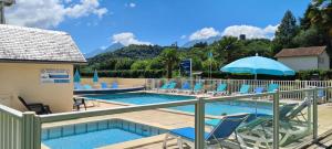 阿戈斯维达洛斯Camping Familial - Parc Aquatique - Grande Aire de Jeux à la Montagne的带椅子和遮阳伞的游泳池