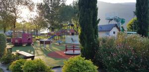 Camping La Châtaigneraie في Agos-Vidalos: حديقة بها ملعب مع معدات لعب